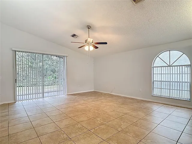 an empty room with windows and ceiling fan