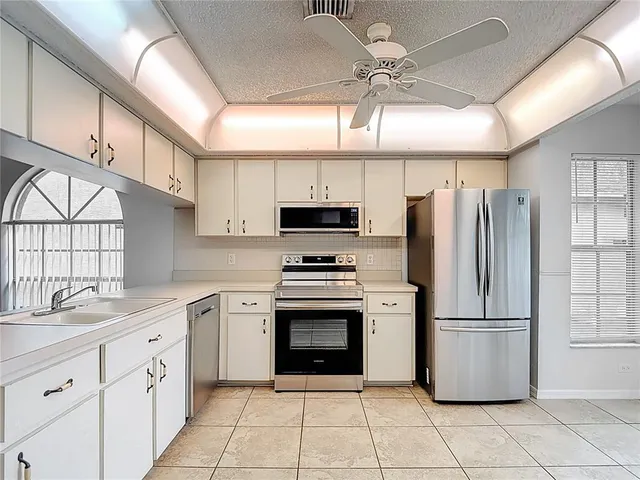 a kitchen with stainless steel appliances granite countertop a refrigerator a sink a stove top oven and a window