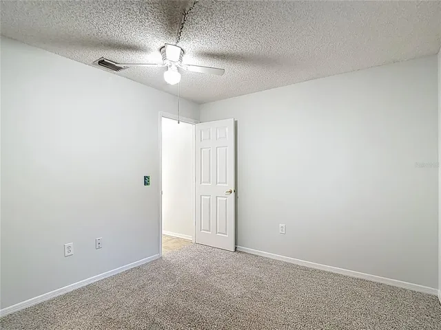 a view of an empty room with a chandelier fan