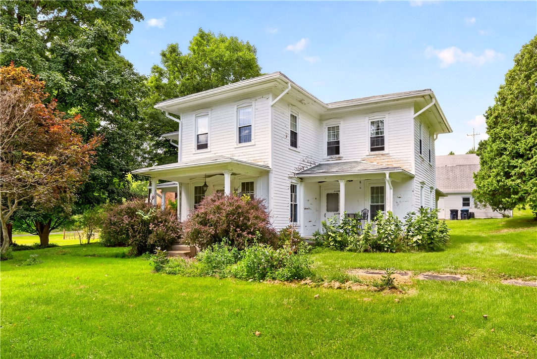 7780 Cold Springs Road Bath, NY 14810 - Photo 2 of 50 Mature trees frame a classic two-story home with a wrap-around front porch and spacious lawn.