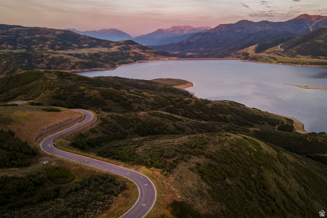 9269 North Sunset Road Kamas, UT 84036 - Photo 12 of 21 Winding paved road traversing a mountainous landscape with a large body of water, distant peaks, and varied natural terrain