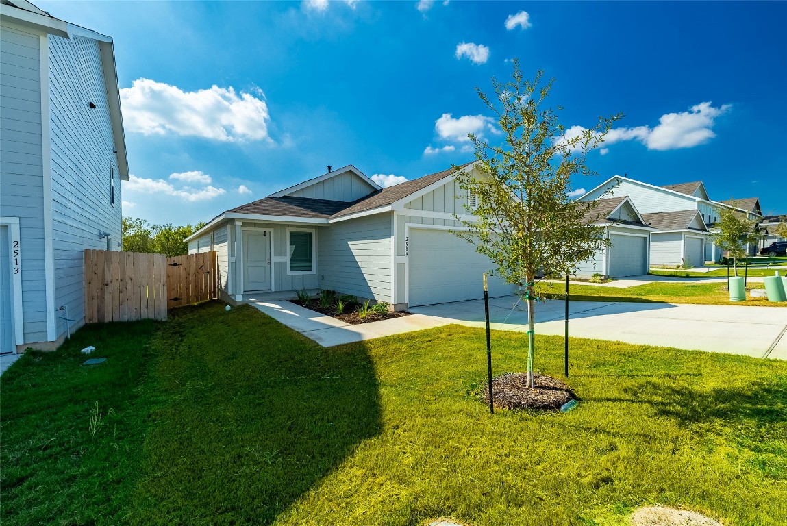 View of front of home with board and batten siding, concrete driveway, an attached garage, and a gate