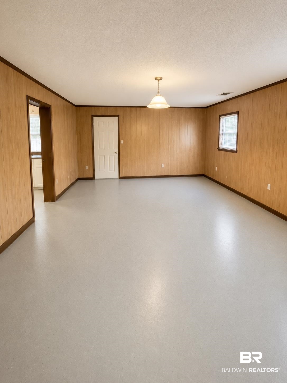 226 Elizabeth Street Evergreen, AL 36401 - Photo 31 of 35 Spacious room with light gray flooring, light wood-look paneling, and dark wood trim