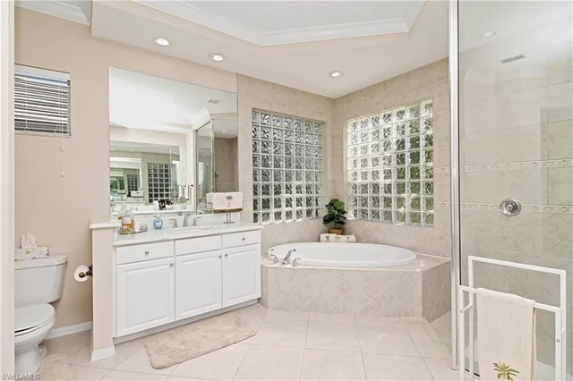 a bathroom with a granite countertop bathtub sink vanity mirror and toilet