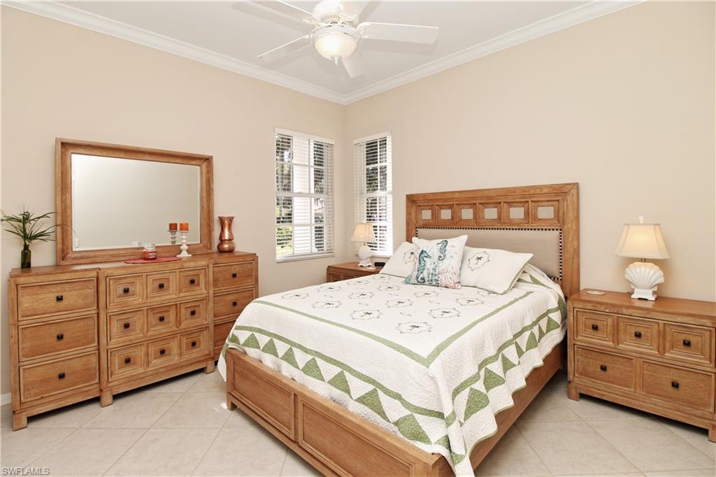 1901 Winding Oaks Way Naples, FL 34109 - Photo 13 of 21 a bedroom with a bed a dresser and a mirror