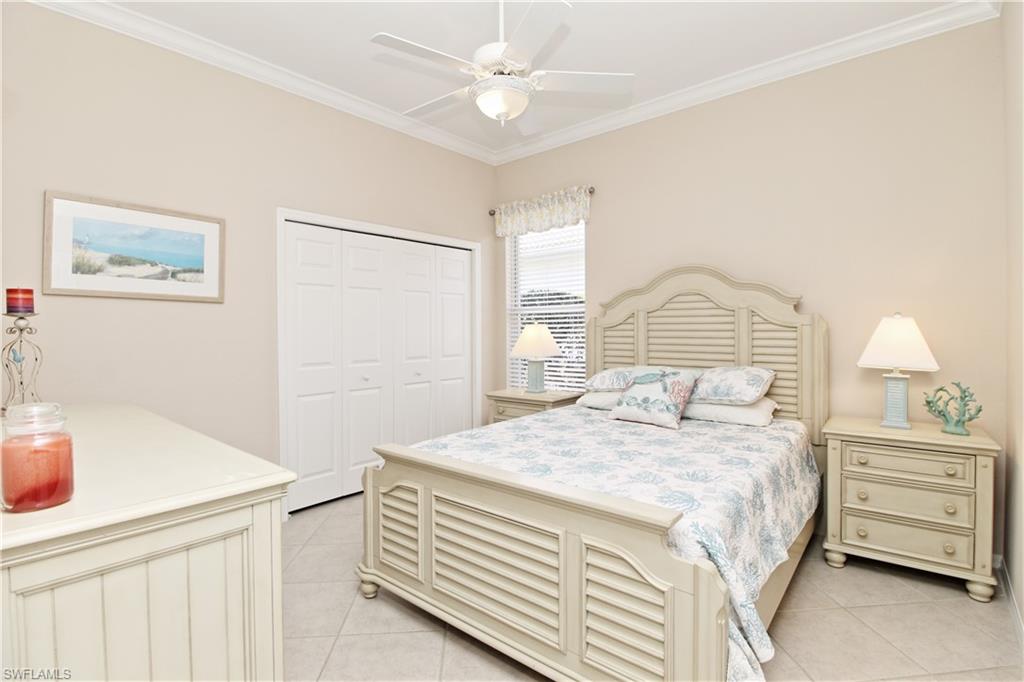 1901 Winding Oaks Way Naples, FL 34109 - Photo 15 of 21 a bedroom with a bed a dresser and a chandelier