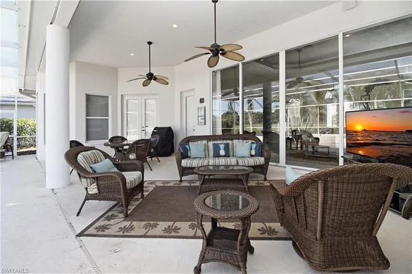 a living room with furniture a flat screen tv and large windows