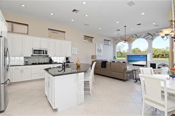 a kitchen with kitchen island granite countertop a sink cabinets and stainless steel appliances
