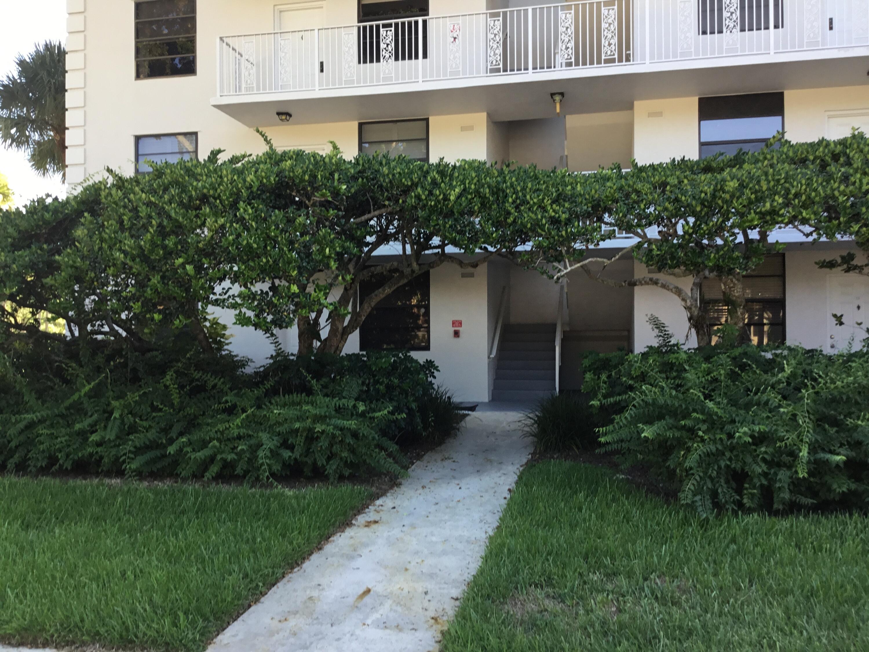 3636 Whitehall Drive, Unit 101 West Palm Beach, FL 33401 - Photo 2 of 16 a front view of a house with a yard and trees