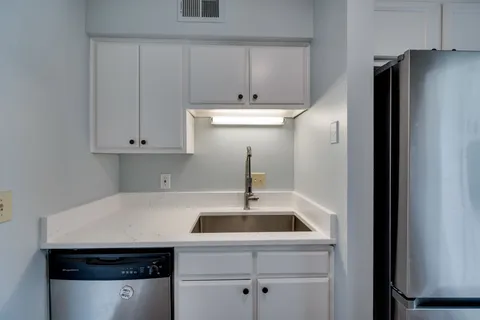a kitchen with a sink a refrigerator and cabinets