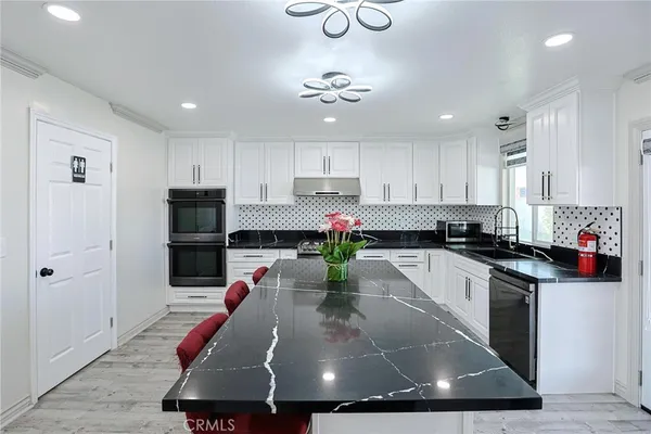 a kitchen with kitchen island granite countertop a sink stainless steel appliances and cabinets