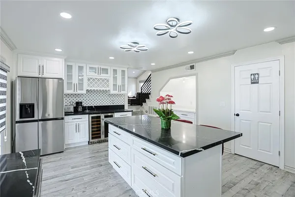 a kitchen with granite countertop kitchen island stainless steel appliances a refrigerator counter space and wooden floor