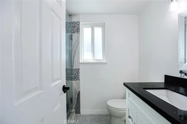 a bathroom with a granite countertop sink toilet a mirror and window