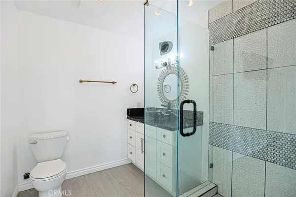 a bathroom with a sink a mirror a glass door a shower and vanity