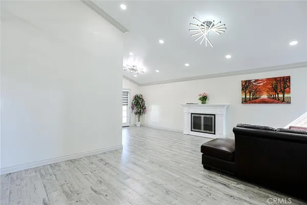 a view of a livingroom with furniture a fireplace wooden floor and chandelier