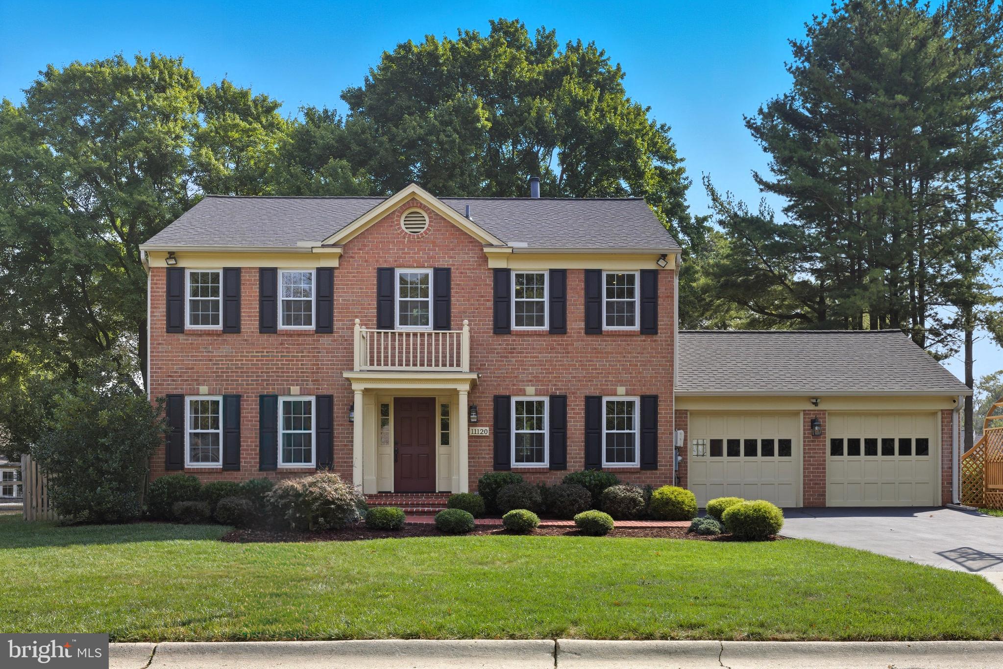a view of a big yard in front of a brick house with large windows