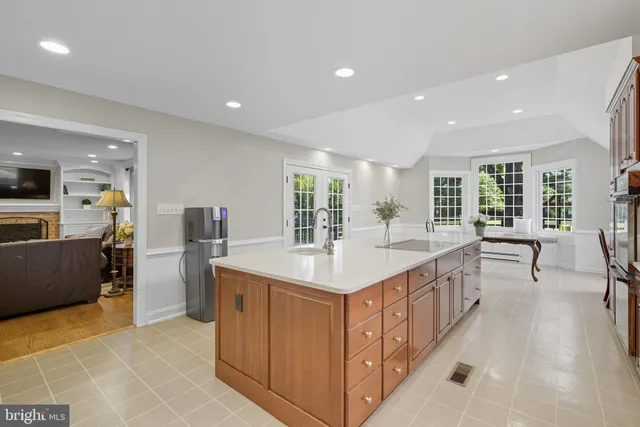 a large kitchen with kitchen island a large window a sink and stainless steel appliances