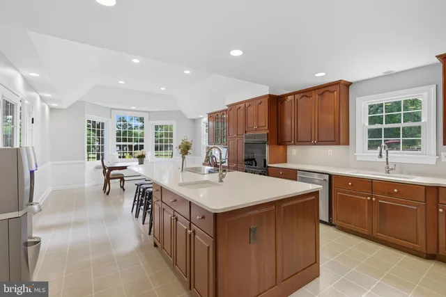 a large kitchen with stainless steel appliances kitchen island granite countertop a refrigerator and a sink