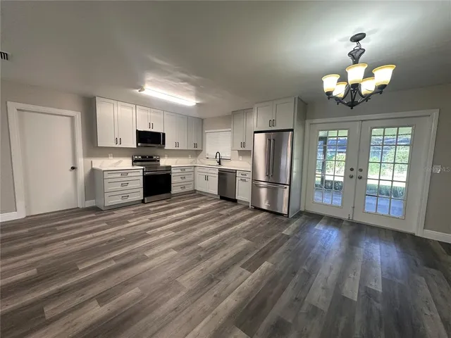 a view of a kitchen with a sink a refrigerator a kitchen island wooden floor and a refrigerator