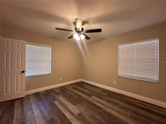 a view of a room with wooden floor and a ceiling fan