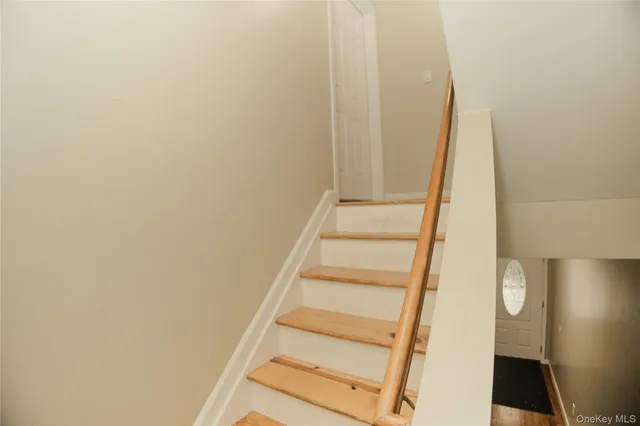a view of staircase with white walls and white door