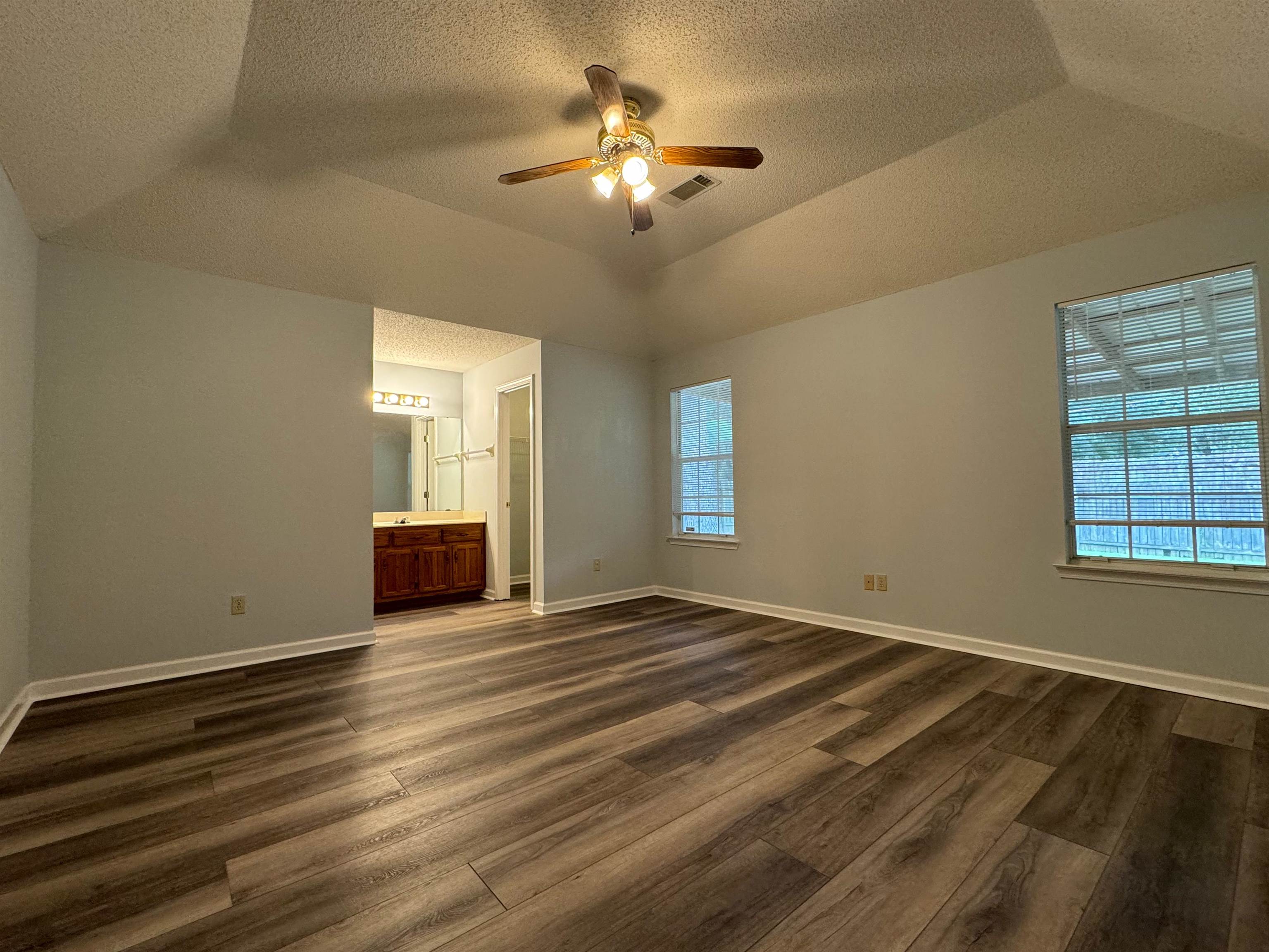 7083 Bryan Station Road Cordova, TN 38018 - Photo 12 of 19 Unfurnished bedroom featuring ceiling fan, a textured ceiling, dark wood-type flooring, ensuite bath, and vaulted ceiling