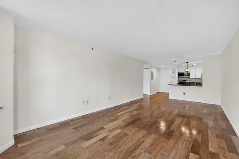 a view of kitchen and empty room with wooden floor