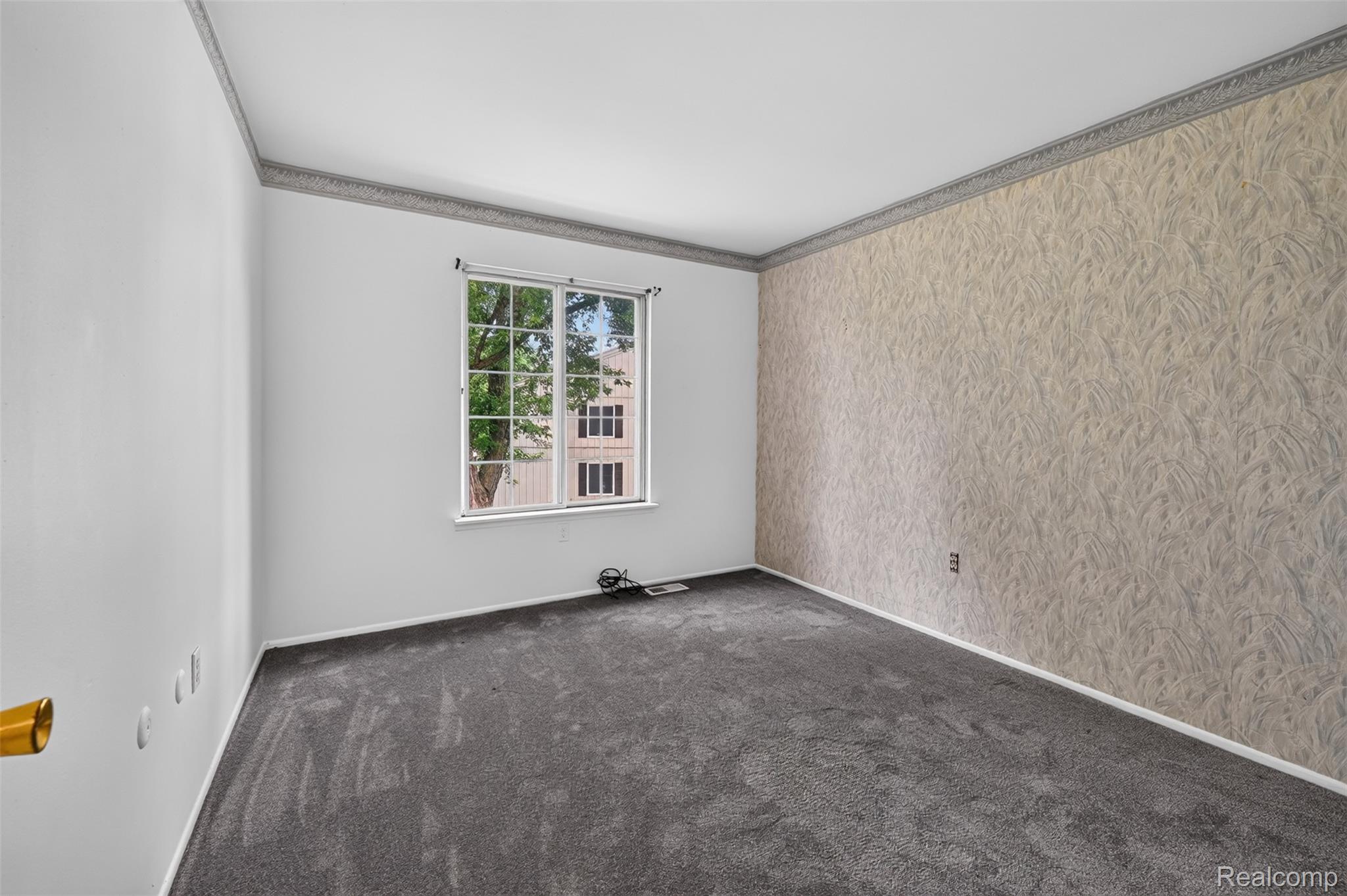 8324 North Genesee Road Mount Morris, MI 48458 - Photo 24 of 33 Carpeted interior space featuring a window with grid panes, textured wallpaper accent wall, and decorative crown molding