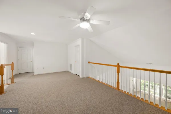 an empty room with a chandelier fan and closet area