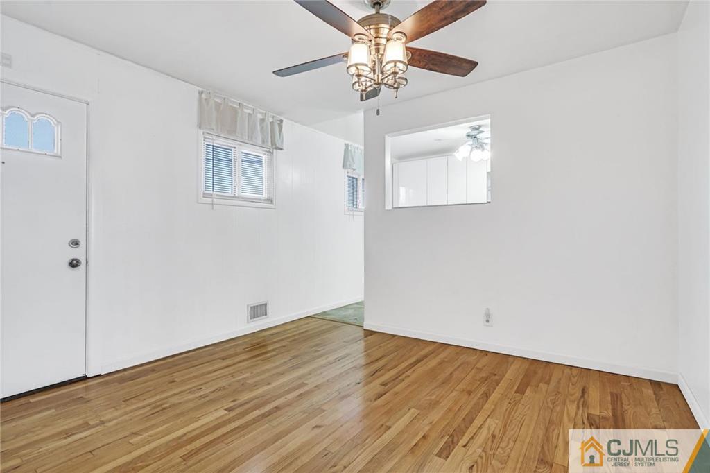 3020 Cheesequake Road Old Bridge, NJ 08859 - Photo 5 of 25 an empty room with wooden floor chandelier fan and windows