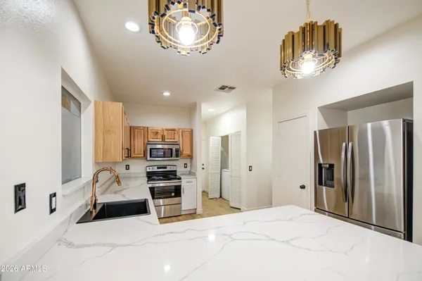 a view of kitchen with stainless steel appliances kitchen island granite countertop furniture and refrigerator