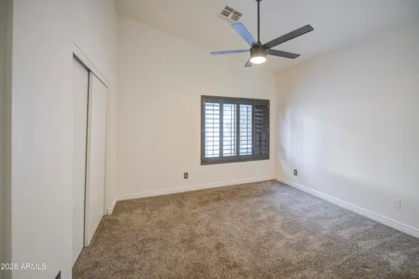 an empty room with a ceiling fan and window