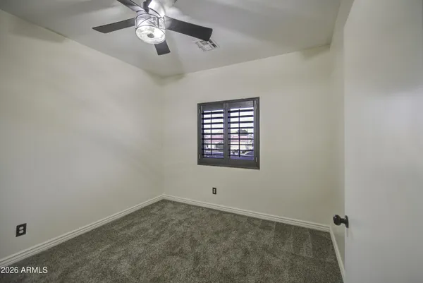 an empty room with windows and fan