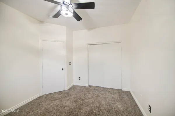 an empty room with ceiling fan and window