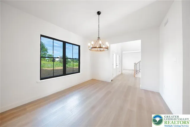 a view of a room with wooden floor chandeliers and kitchen view