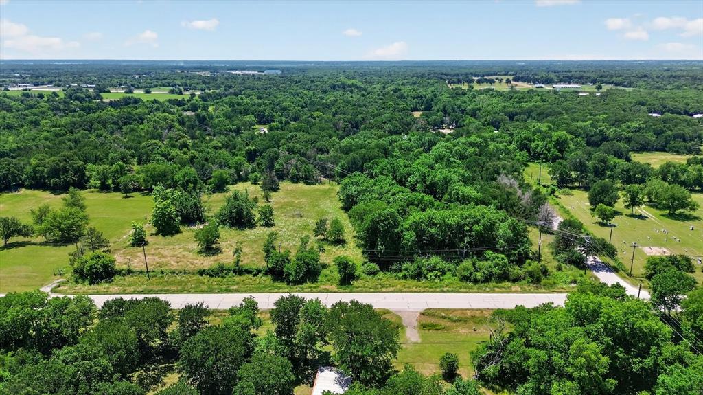 613 Main Street Quinlan, TX 75474 - Photo 2 of 16 Acreage featuring a paved road frontage, mature trees, and open grassy areas, surrounded by substantial wooded areas