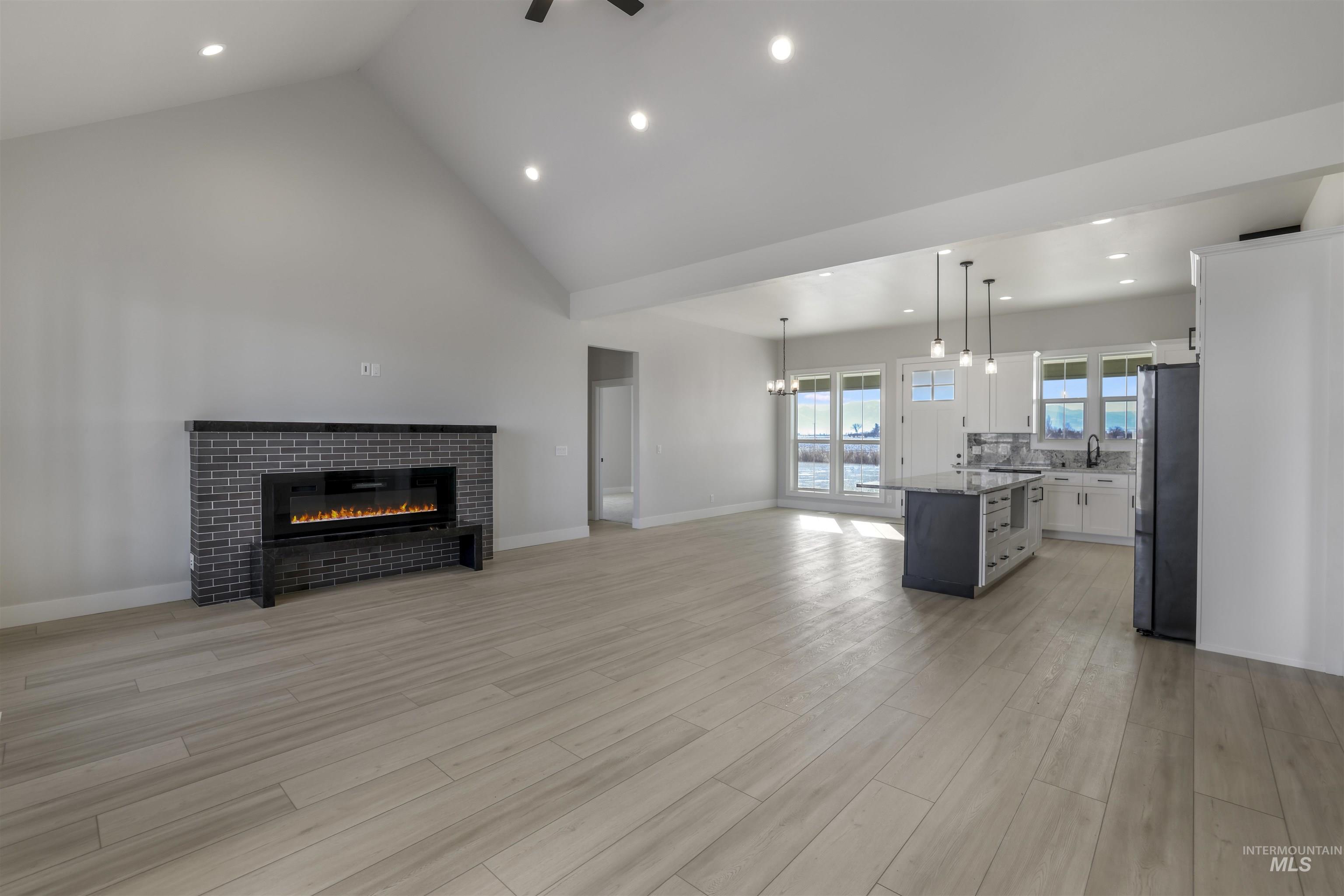 262 Ferdinand Circle Burley, ID 83318 - Photo 4 of 50 Unfurnished living room with a glass covered fireplace, high vaulted ceiling, recessed lighting, light wood-type flooring, and a chandelier