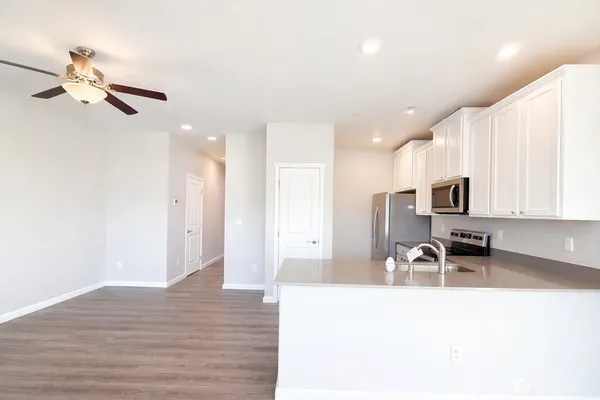 a view of a kitchen with kitchen island a sink stainless steel appliances and cabinets
