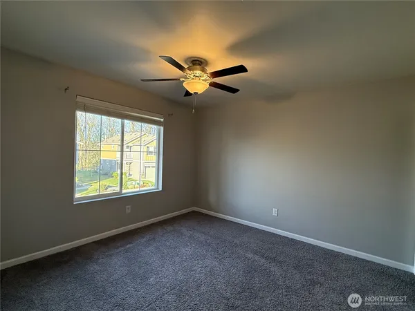 an empty room with windows and fan