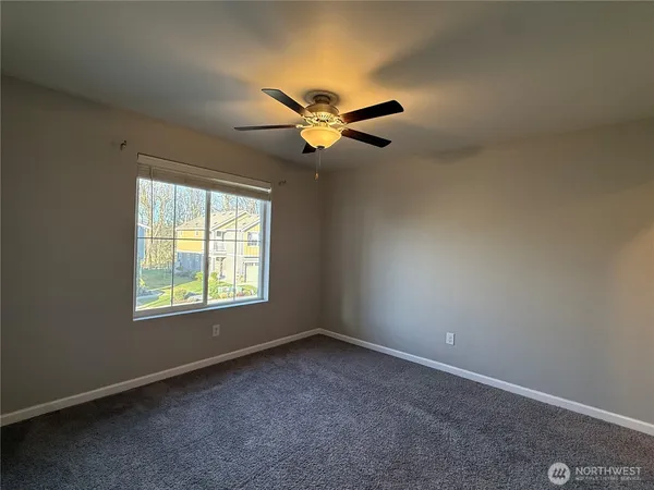 an empty room with a window and a fan