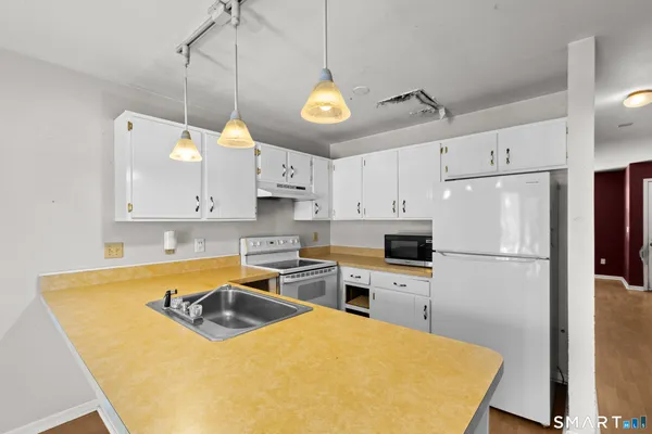 a kitchen with stainless steel appliances granite countertop a sink a stove a refrigerator a center island a stove and white cabinets