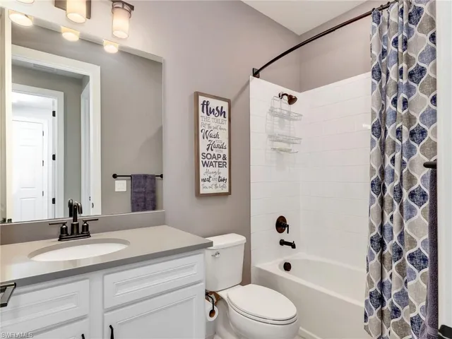 a bathroom with a granite countertop sink toilet a mirror a vanity and shower