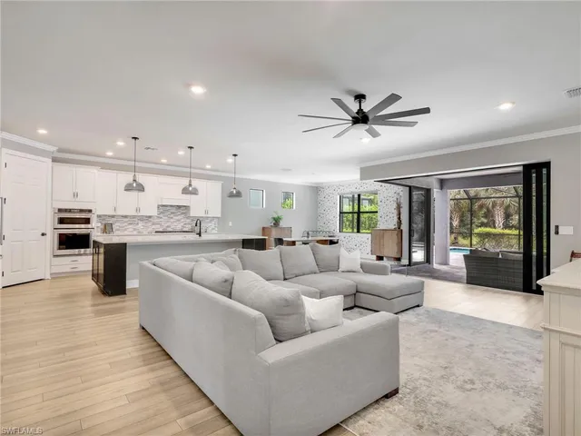 a living room with furniture kitchen area and a wooden floor