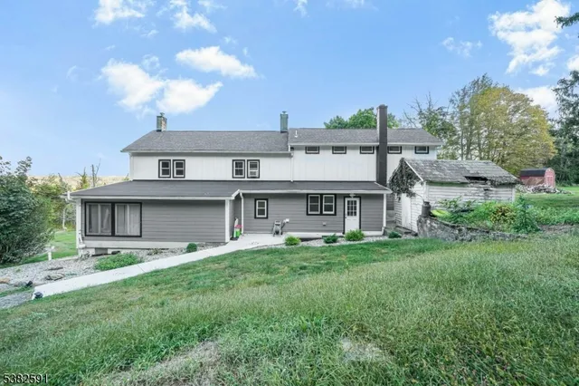 a view of a house with a big yard and large trees