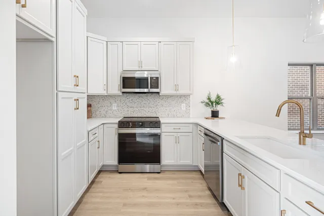 a kitchen with white cabinets sink and stainless steel appliances