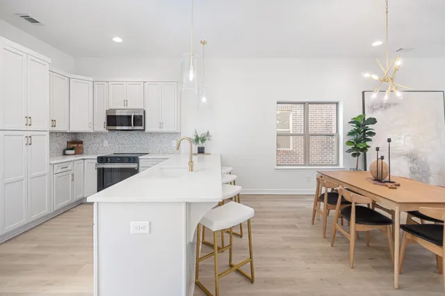 a kitchen with kitchen island granite countertop a sink and a stove top oven with wooden floor