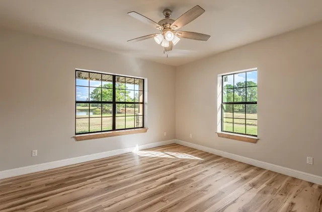 a view of an empty room with window and wooden floor