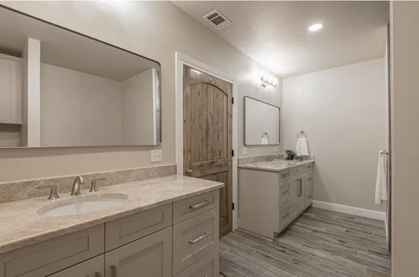 a view of a hallway with wooden floor and a bathroom