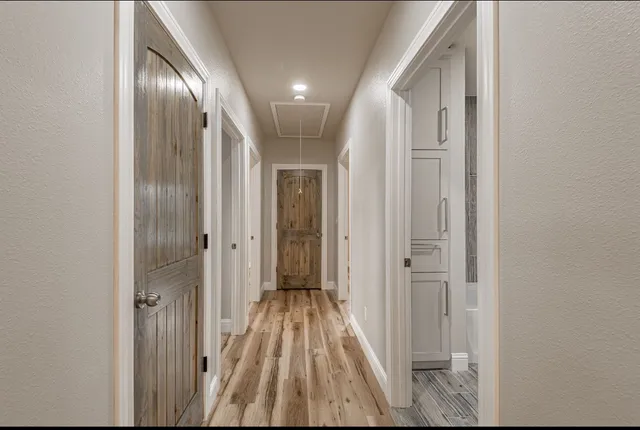 a view of a hallway with wooden floor and a bathroom