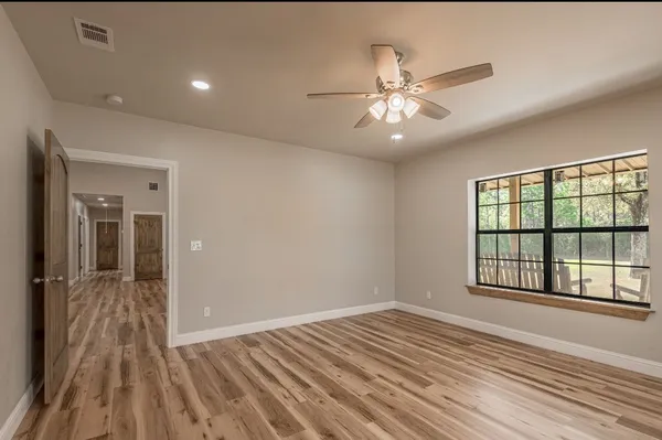 a view of an empty room with a window and wooden floor